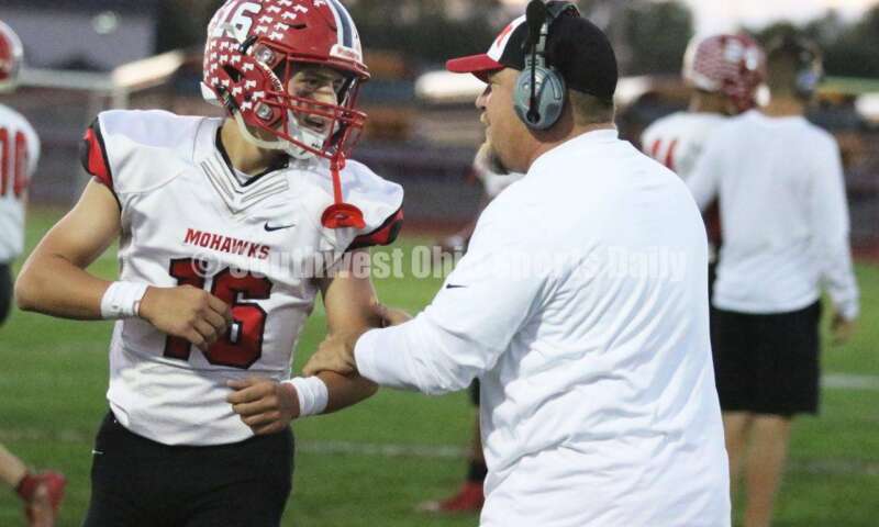 Madison High School's Alex Rumping (16) talks to assistant coach Steve Poff on the sideline Oct. 3, 2019, during a Southwestern Buckeye League football game at Dixie. The visiting Mohawks won 48-13. RICK CASSANO/STAFF