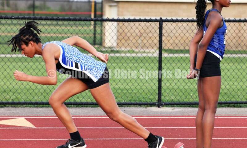 Hamilton High School's Danity Sims (right) secures the block for teammate Alannah Williams in the girls 300-meter hurdles April 16, 2024, during the Dale Plank Invitational track & field meet at Talawanda. RICK CASSANO/STAFF