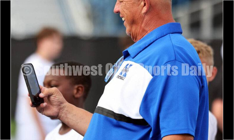 Hamilton High School coach Arvie Crouch checks out his phone during youth football camp June 20, 2025, at Virgil Schwarm Stadium in Hamilton. RICK CASSANO/STAFF