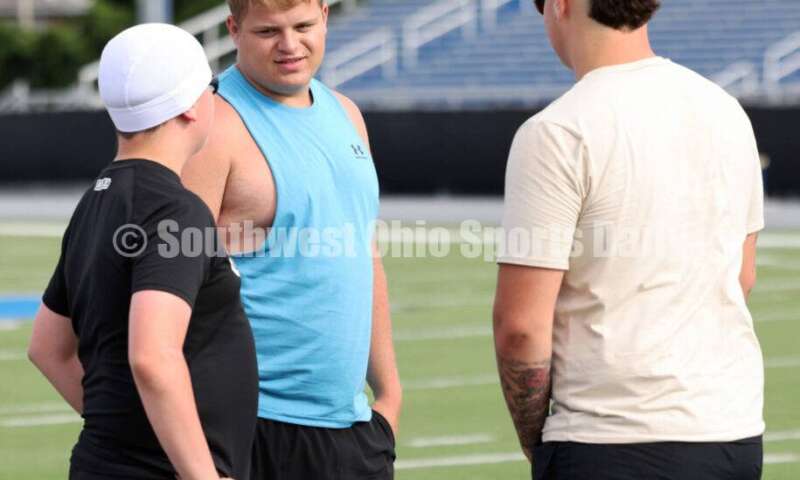 Hamilton High School's Jett Phillips (middle) and Tyler Hale (right) talk during youth football camp June 20, 2025, at Virgil Schwarm Stadium in Hamilton. RICK CASSANO/STAFF